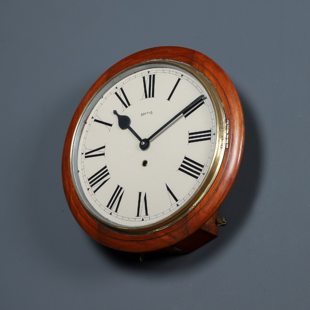 An antique Smiths circular wall clock with a turned mahogany surround, off-white dial plate, black Roman numerals, and brass bezel. View III