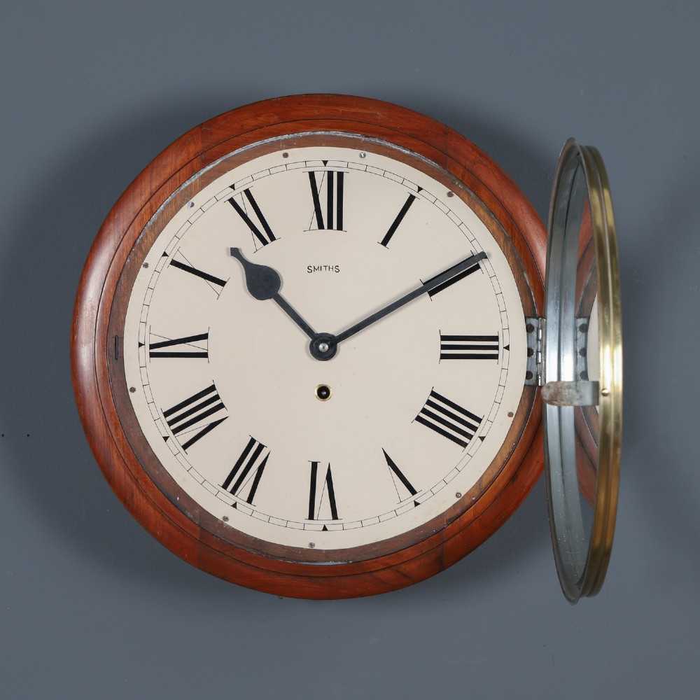An antique Smiths circular wall clock with a turned mahogany surround, off-white dial plate, black Roman numerals, and brass bezel. View VII