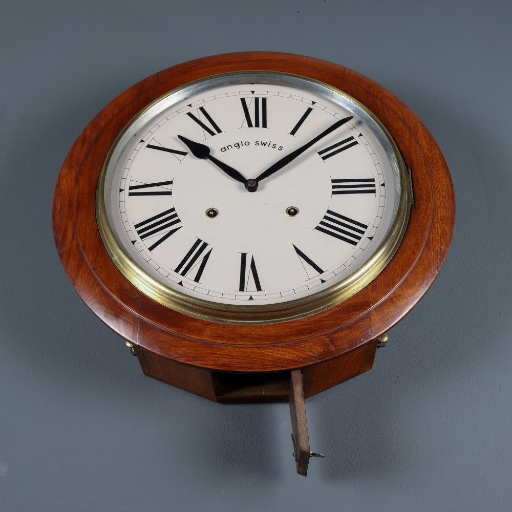 A circular antique wall clock featuring a turned mahogany frame, brass bezel, and white dial with black Roman numerals marked Anglo Swiss. View VI