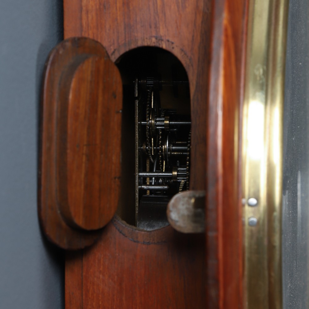 A circular antique wall clock featuring a turned mahogany frame, brass bezel, and white dial with black Roman numerals marked Anglo Swiss. View XI