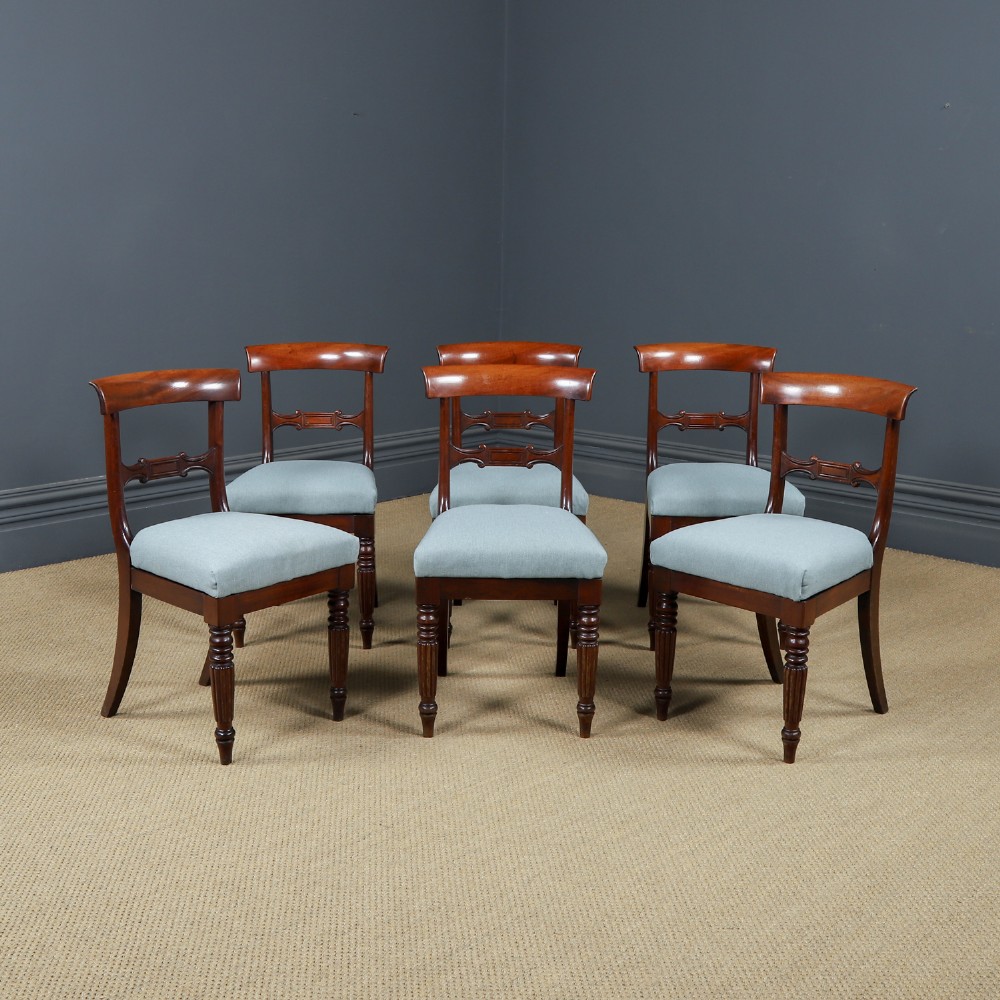 A set of six antique mahogany dining chairs featuring curved top rails, carved horizontal splats, fluted turned front legs, and light blue upholstered seats.