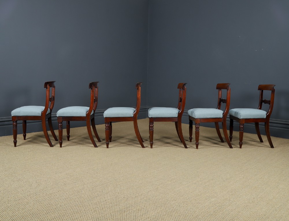 A set of six antique mahogany dining chairs featuring curved top rails, carved horizontal splats, fluted turned front legs, and light blue upholstered seats. View XI