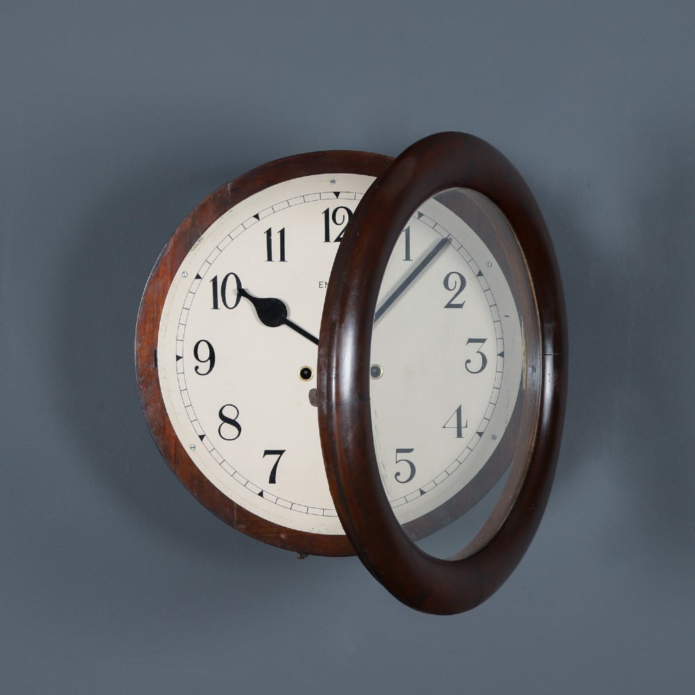 A circular mahogany wall clock with a cream dial, black Arabic numerals, black metal hands, two brass winding holes, and the Enfield maker name printed in the centre. View II