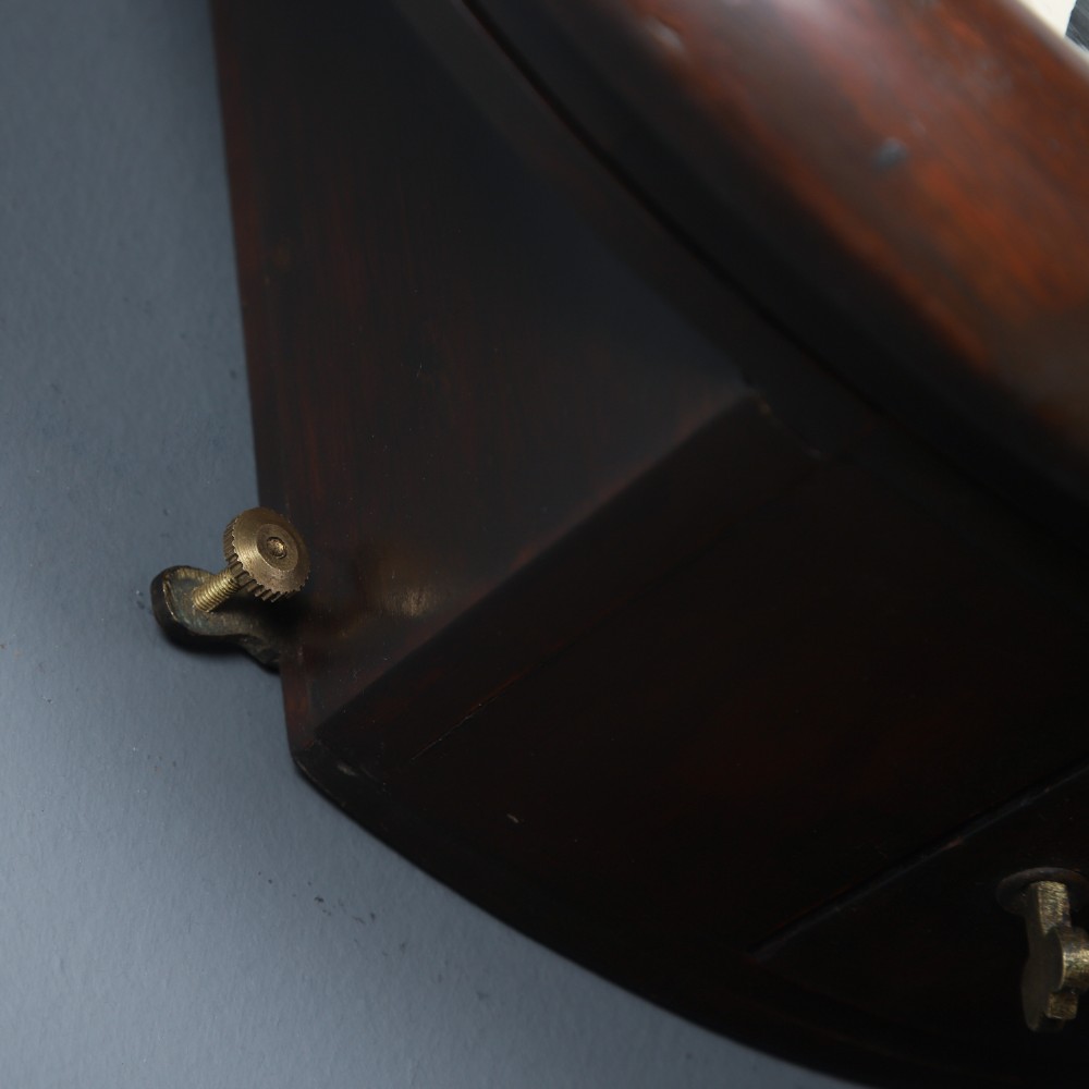A circular mahogany wall clock with a cream dial, black Arabic numerals, black metal hands, two brass winding holes, and the Enfield maker name printed in the centre. View VI