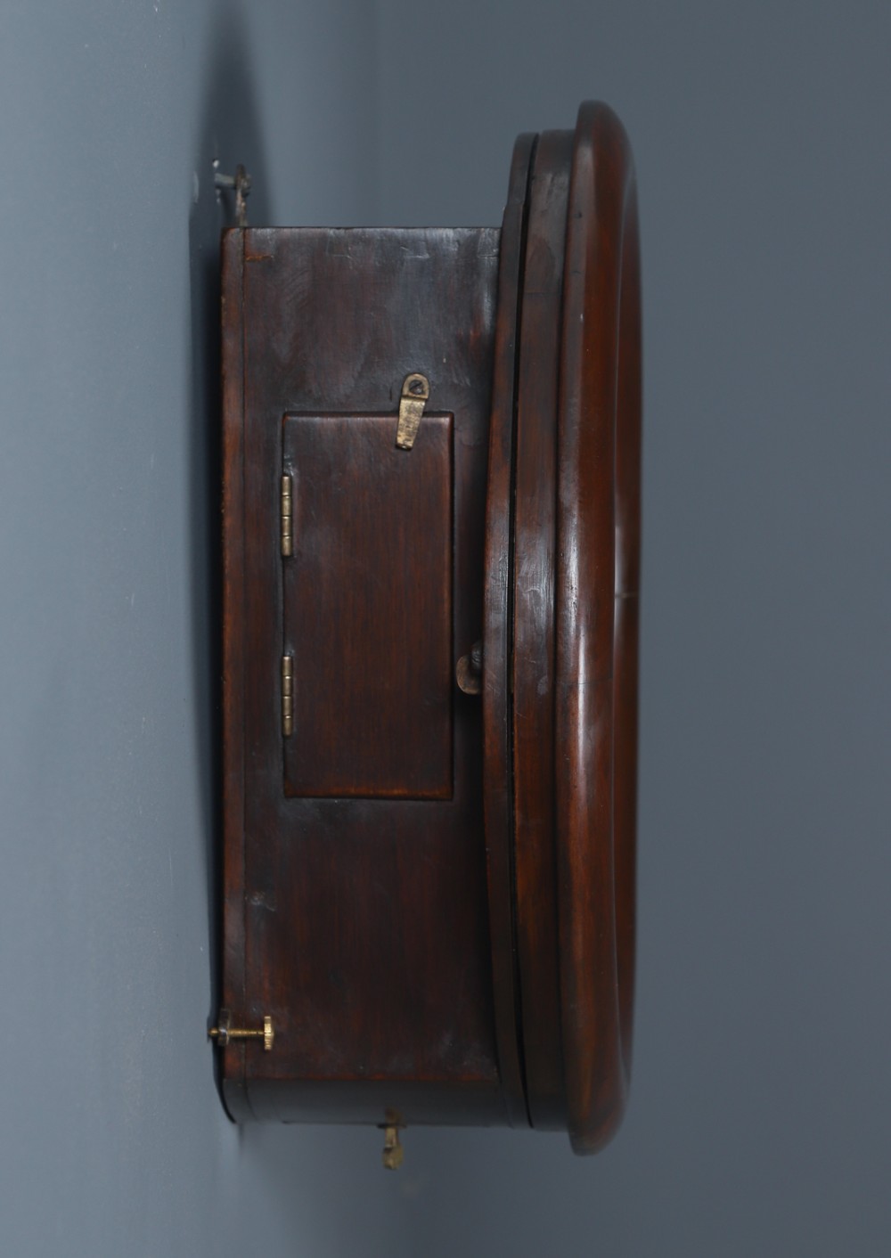 A circular mahogany wall clock with a cream dial, black Arabic numerals, black metal hands, two brass winding holes, and the Enfield maker name printed in the centre. View IX