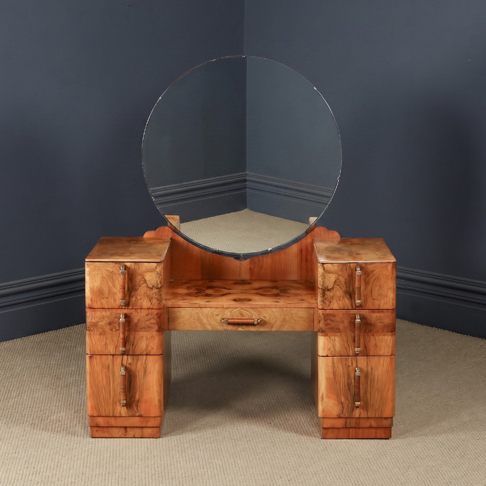 An Art Deco burr walnut pedestal dressing table featuring a large circular central mirror, a kneehole drawer, and three stacked drawers on each pedestal with vertical handles.