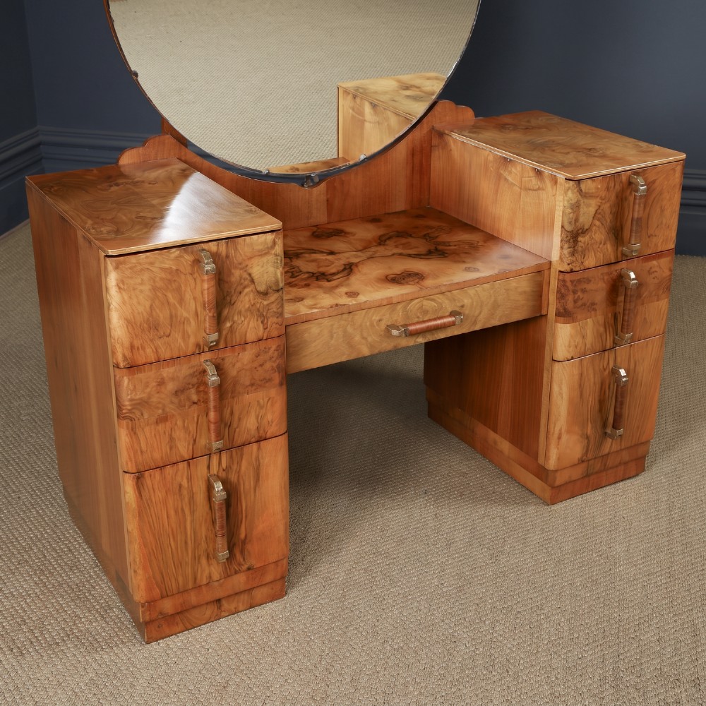 An Art Deco burr walnut pedestal dressing table featuring a large circular central mirror, a kneehole drawer, and three stacked drawers on each pedestal with vertical handles. View II