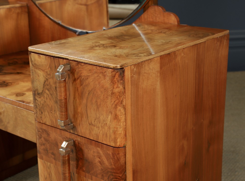 An Art Deco burr walnut pedestal dressing table featuring a large circular central mirror, a kneehole drawer, and three stacked drawers on each pedestal with vertical handles. View VIII