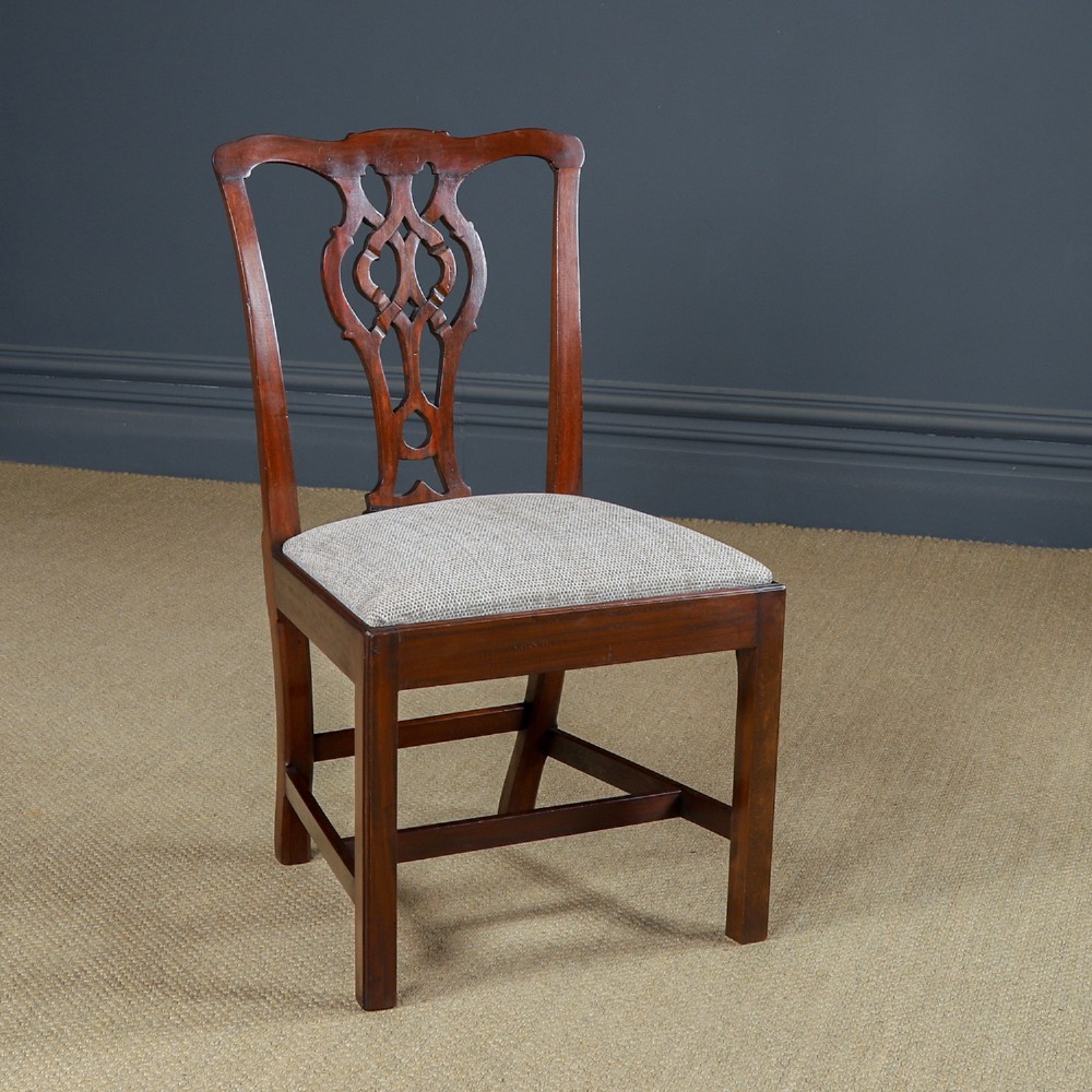 A Georgian mahogany side chair with a pierced carved back splat, square legs connected by stretchers, and a neutral textured seat upholstery.