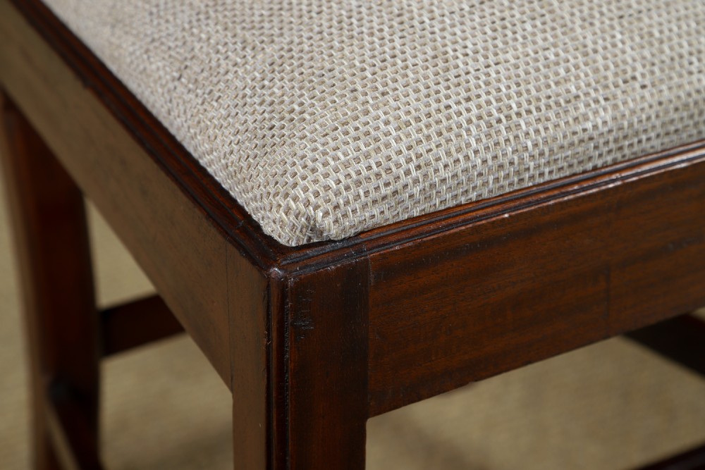 A Georgian mahogany side chair with a pierced carved back splat, square legs connected by stretchers, and a neutral textured seat upholstery. View V