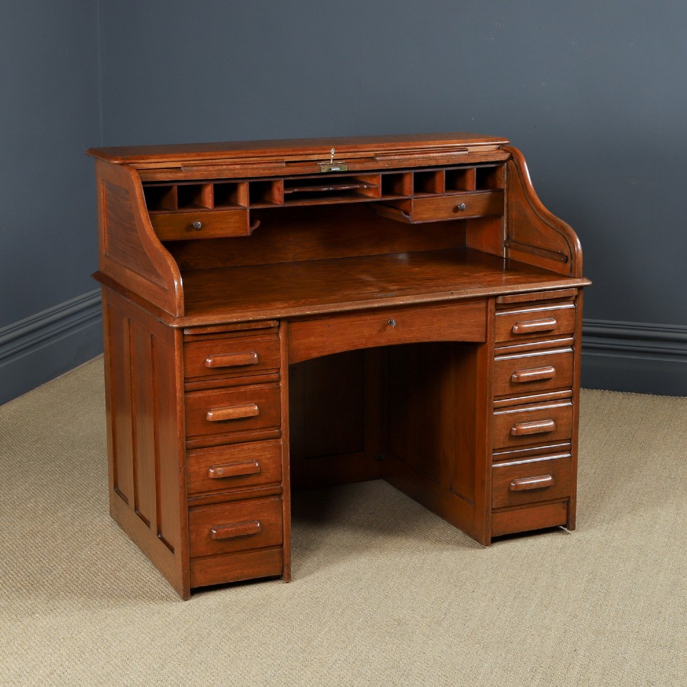An Edwardian warm brown oak twin-pedestal rolltop desk featuring a flexible slatted wooden tambour shutter open to reveal internal pigeonholes above nine drawers with wooden cup handles.