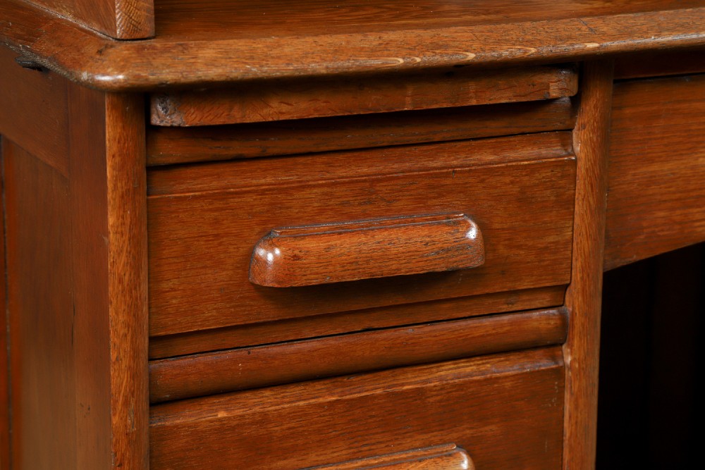 An Edwardian warm brown oak twin-pedestal rolltop desk featuring a flexible slatted wooden tambour shutter open to reveal internal pigeonholes above nine drawers with wooden cup handles. View III