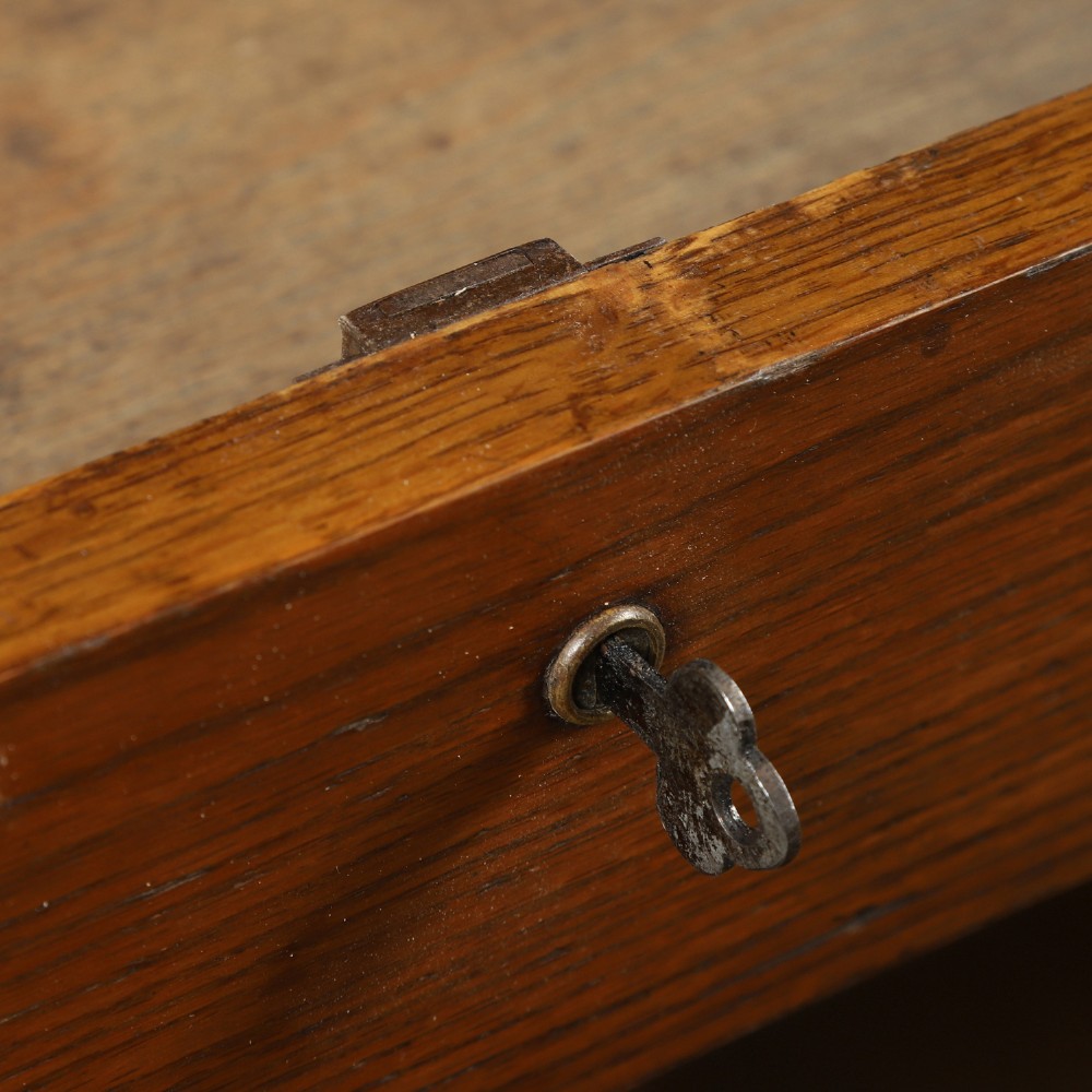 An Edwardian warm brown oak twin-pedestal rolltop desk featuring a flexible slatted wooden tambour shutter open to reveal internal pigeonholes above nine drawers with wooden cup handles. View XIII