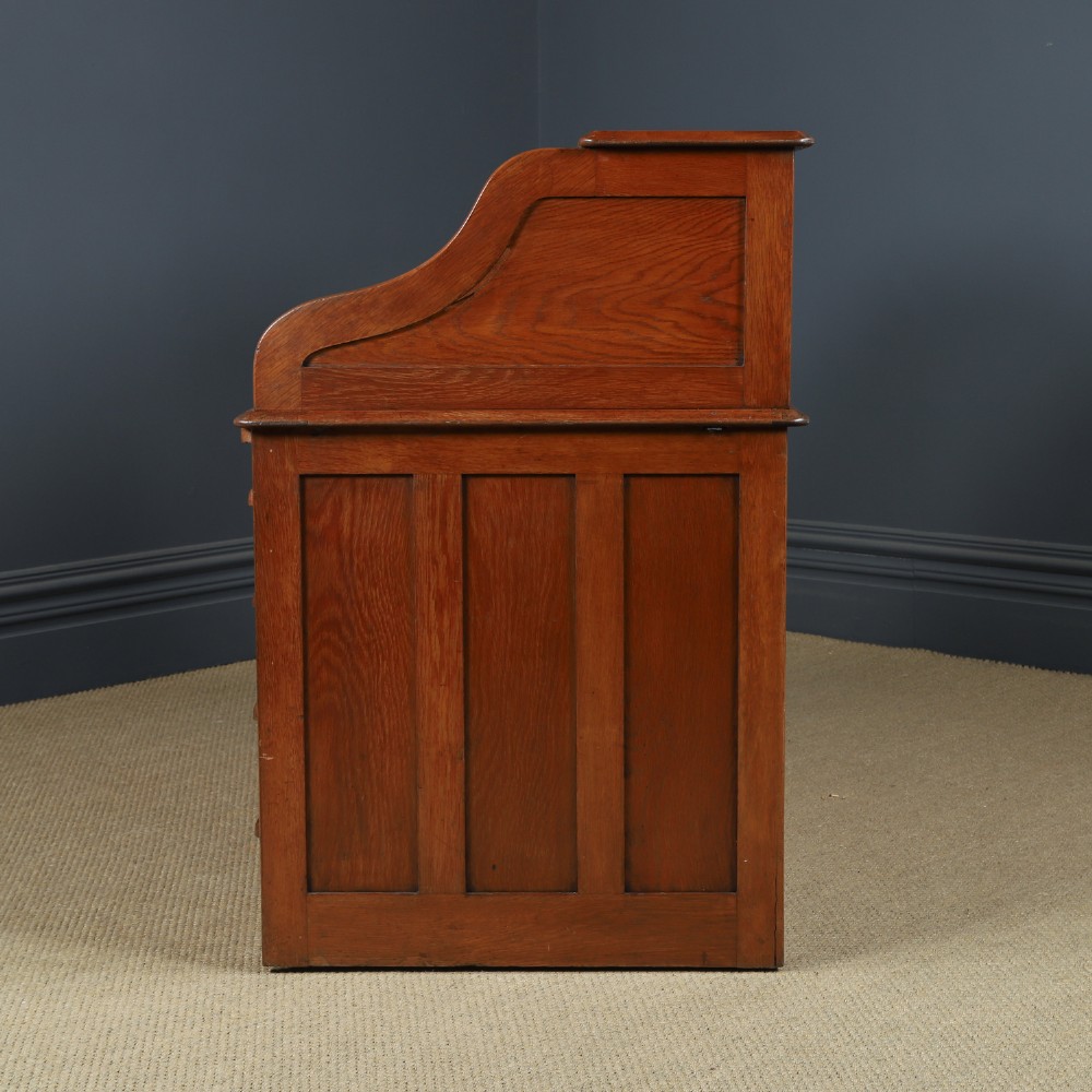 An Edwardian warm brown oak twin-pedestal rolltop desk featuring a flexible slatted wooden tambour shutter open to reveal internal pigeonholes above nine drawers with wooden cup handles. View XIV