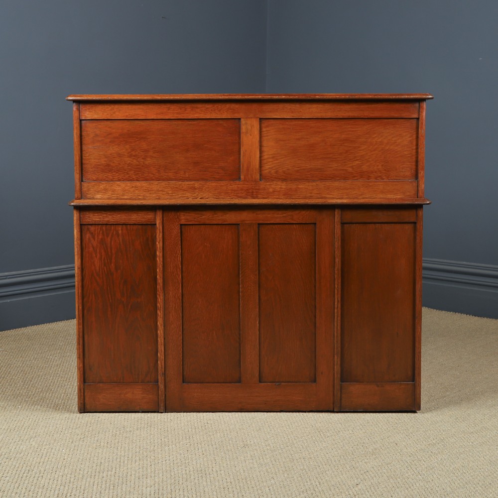 An Edwardian warm brown oak twin-pedestal rolltop desk featuring a flexible slatted wooden tambour shutter open to reveal internal pigeonholes above nine drawers with wooden cup handles. View XV