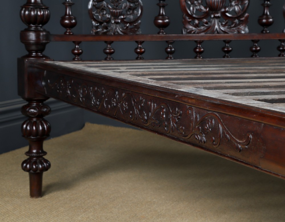 An Anglo-Indian mahogany four poster bed featuring carved turned posts, an ornate headboard, and a spindle footboard. View III