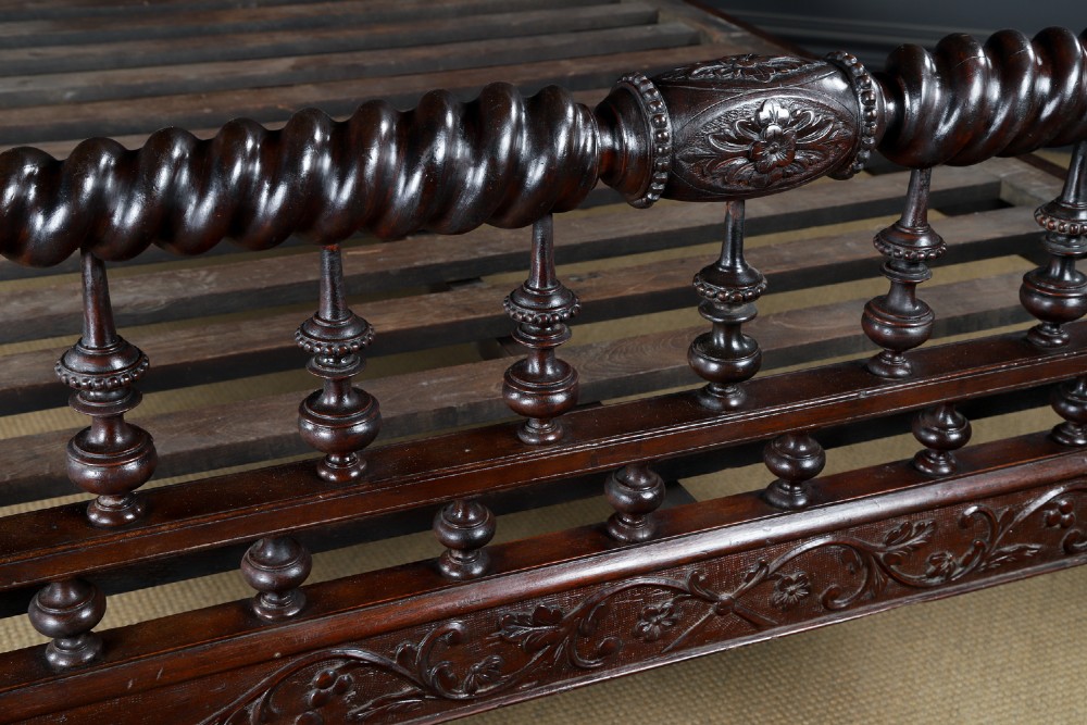An Anglo-Indian mahogany four poster bed featuring carved turned posts, an ornate headboard, and a spindle footboard. View VI