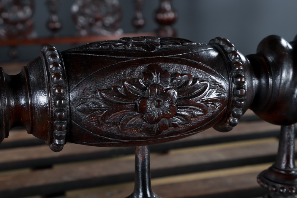 An Anglo-Indian mahogany four poster bed featuring carved turned posts, an ornate headboard, and a spindle footboard. View VII
