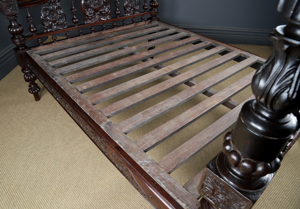 An Anglo-Indian mahogany four poster bed featuring carved turned posts, an ornate headboard, and a spindle footboard. View VIII