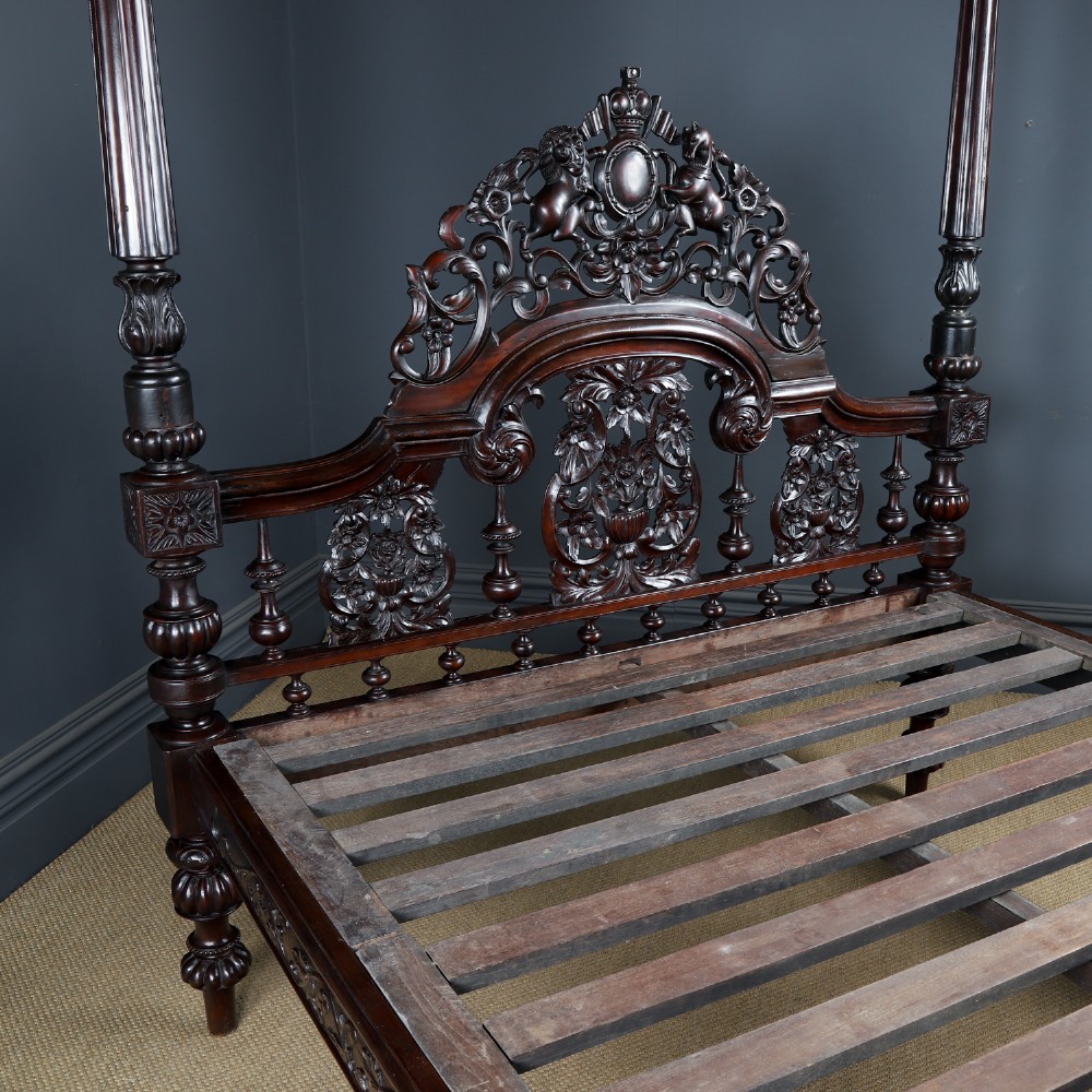 An Anglo-Indian mahogany four poster bed featuring carved turned posts, an ornate headboard, and a spindle footboard. View IX