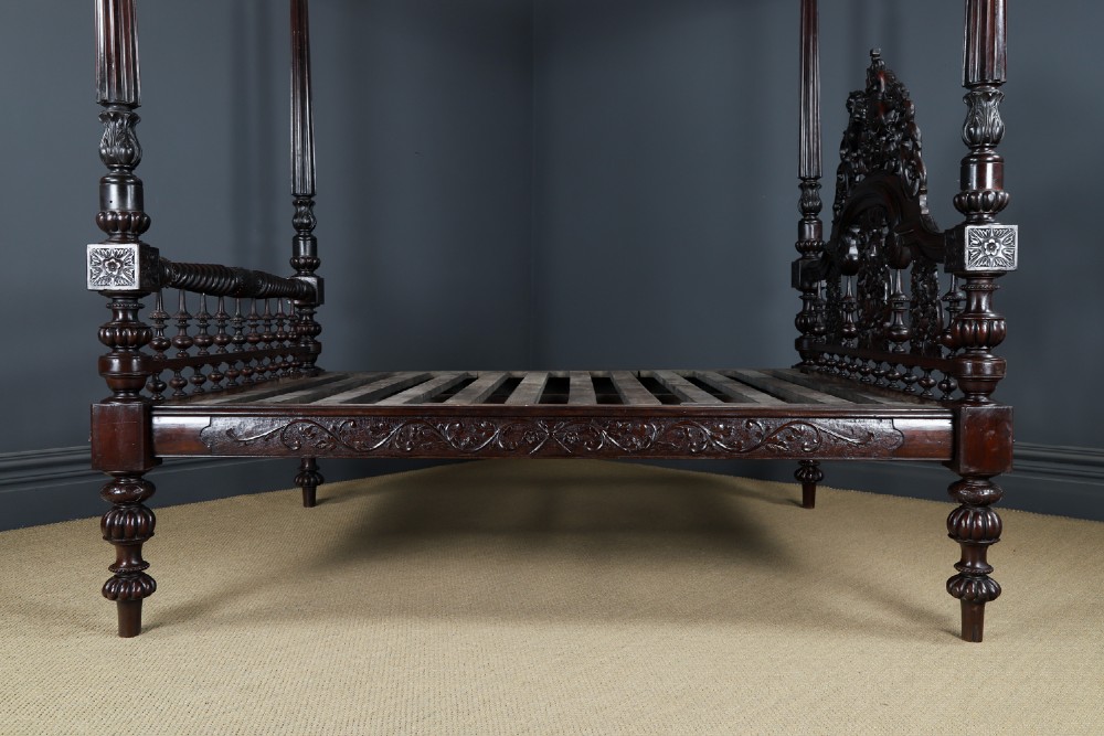 An Anglo-Indian mahogany four poster bed featuring carved turned posts, an ornate headboard, and a spindle footboard. View XIII