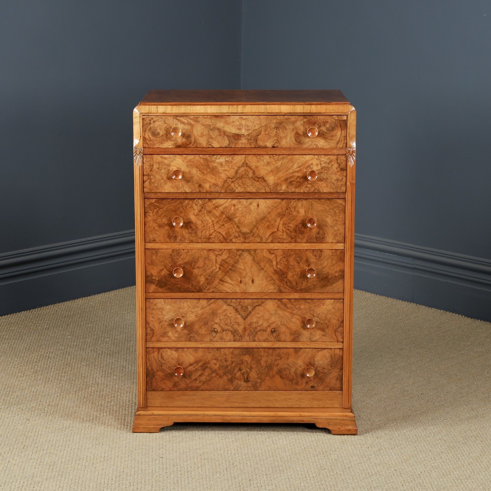 An Art Deco chest of drawers in figured burr walnut featuring six graduated drawers with turned wooden handles and carved shoulder details.