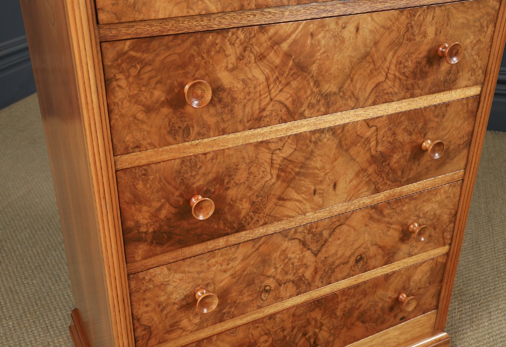 An Art Deco chest of drawers in figured burr walnut featuring six graduated drawers with turned wooden handles and carved shoulder details. View VI