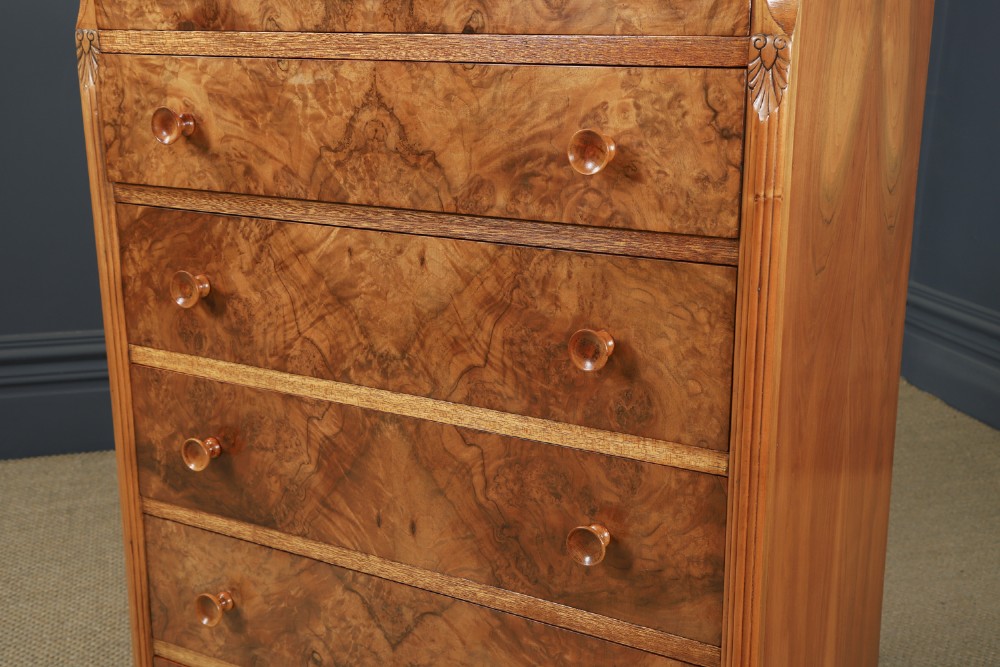 An Art Deco chest of drawers in figured burr walnut featuring six graduated drawers with turned wooden handles and carved shoulder details. View XI
