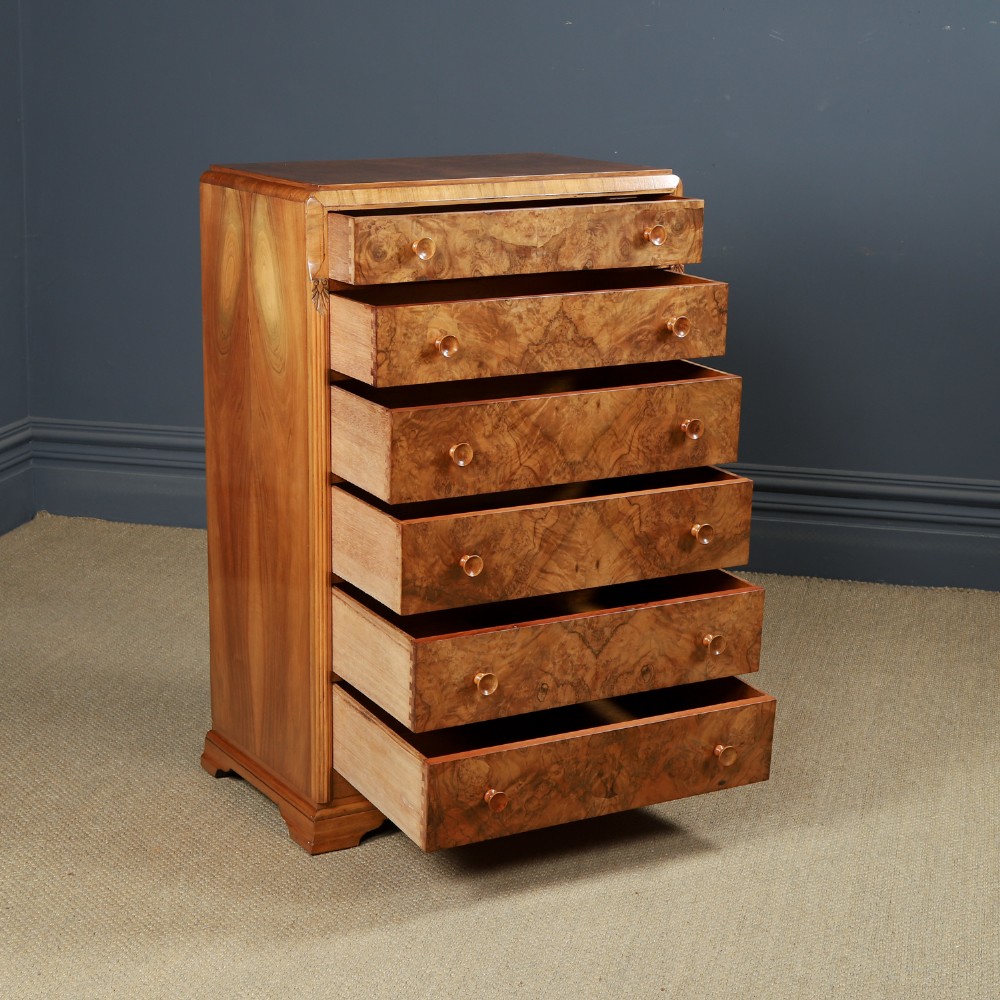 An Art Deco chest of drawers in figured burr walnut featuring six graduated drawers with turned wooden handles and carved shoulder details. View XIII