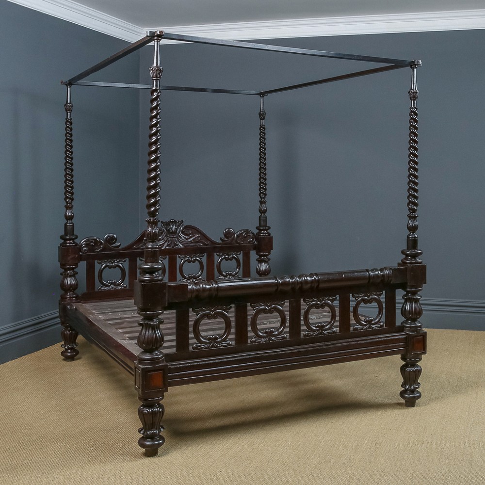 An antique dark timber king-size four-poster bed featuring spiral turned posts, a carved footboard with circular cut-out details, and an upper canopy frame. View II