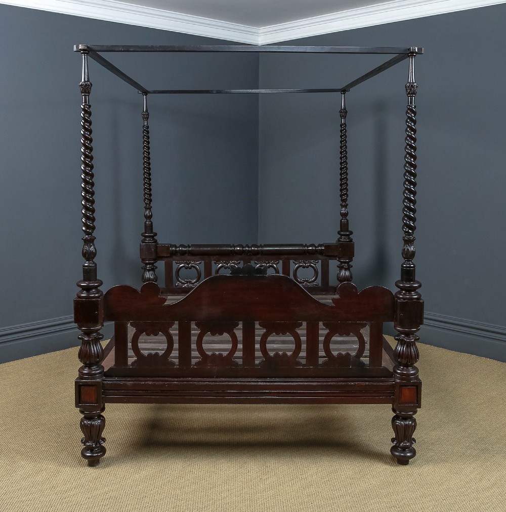 An antique dark timber king-size four-poster bed featuring spiral turned posts, a carved footboard with circular cut-out details, and an upper canopy frame. View XI