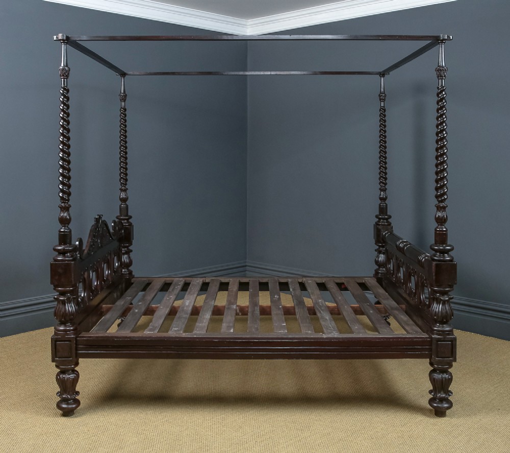 An antique dark timber king-size four-poster bed featuring spiral turned posts, a carved footboard with circular cut-out details, and an upper canopy frame. View XII