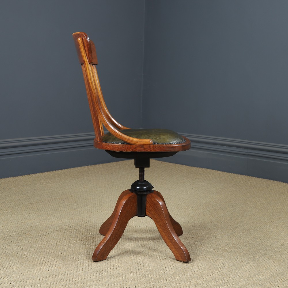 A George V period golden oak revolving desk chair featuring a curved spindle backrest, quadruped base, and a padded green leather seat secured with brass studs. View VII