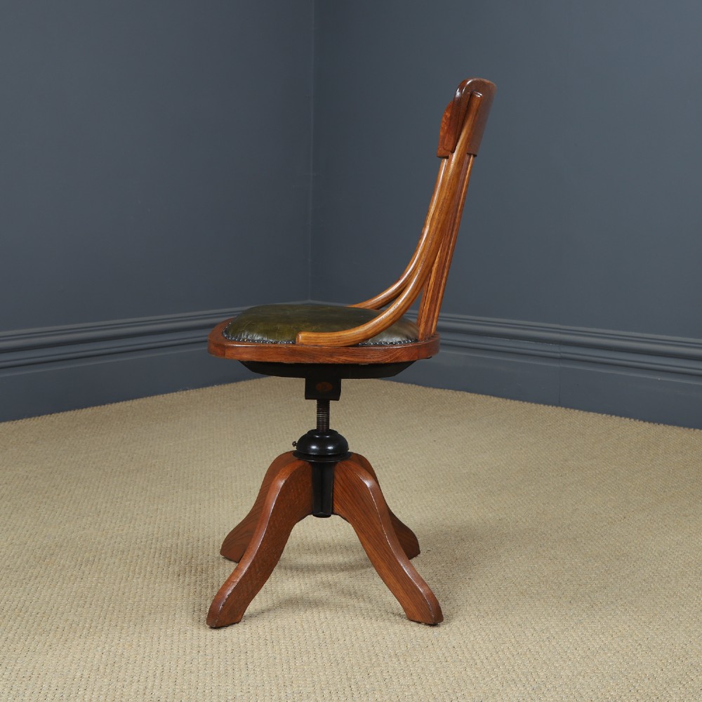 A George V period golden oak revolving desk chair featuring a curved spindle backrest, quadruped base, and a padded green leather seat secured with brass studs. View VIII