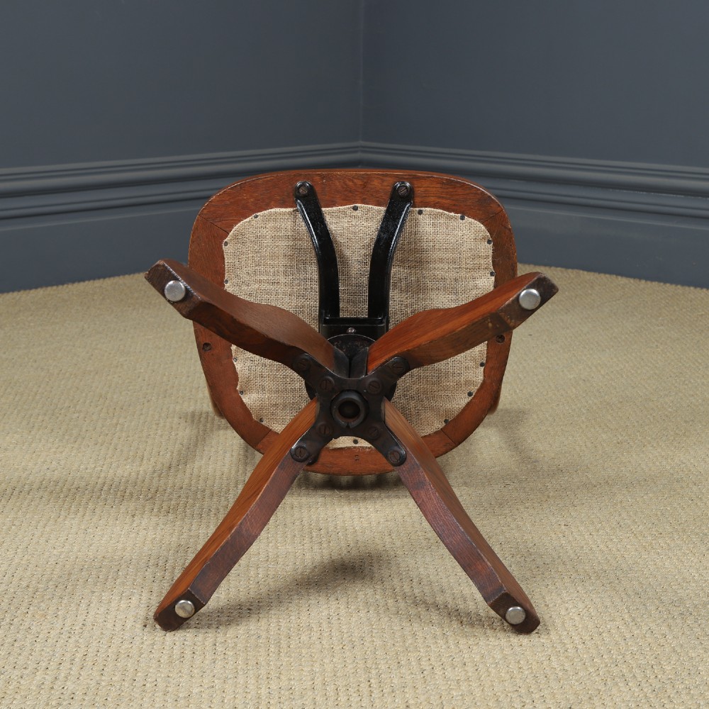 A George V period golden oak revolving desk chair featuring a curved spindle backrest, quadruped base, and a padded green leather seat secured with brass studs. View XII