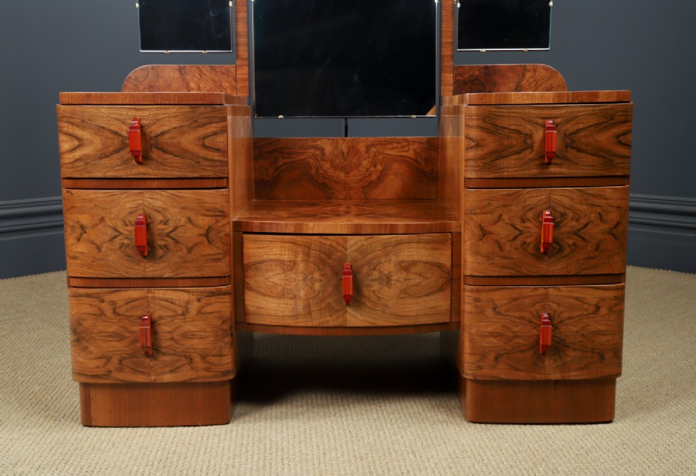 An Art Deco figured walnut dressing table featuring twin pedestal drawers, a central curved drawer, red handles, and a three-panel upright mirror. View II