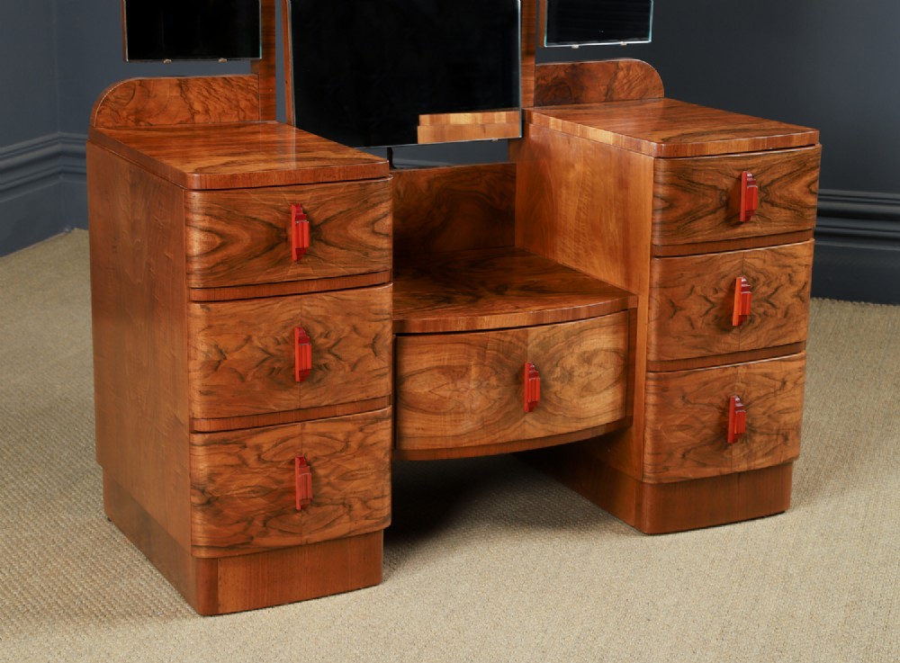 An Art Deco figured walnut dressing table featuring twin pedestal drawers, a central curved drawer, red handles, and a three-panel upright mirror. View III