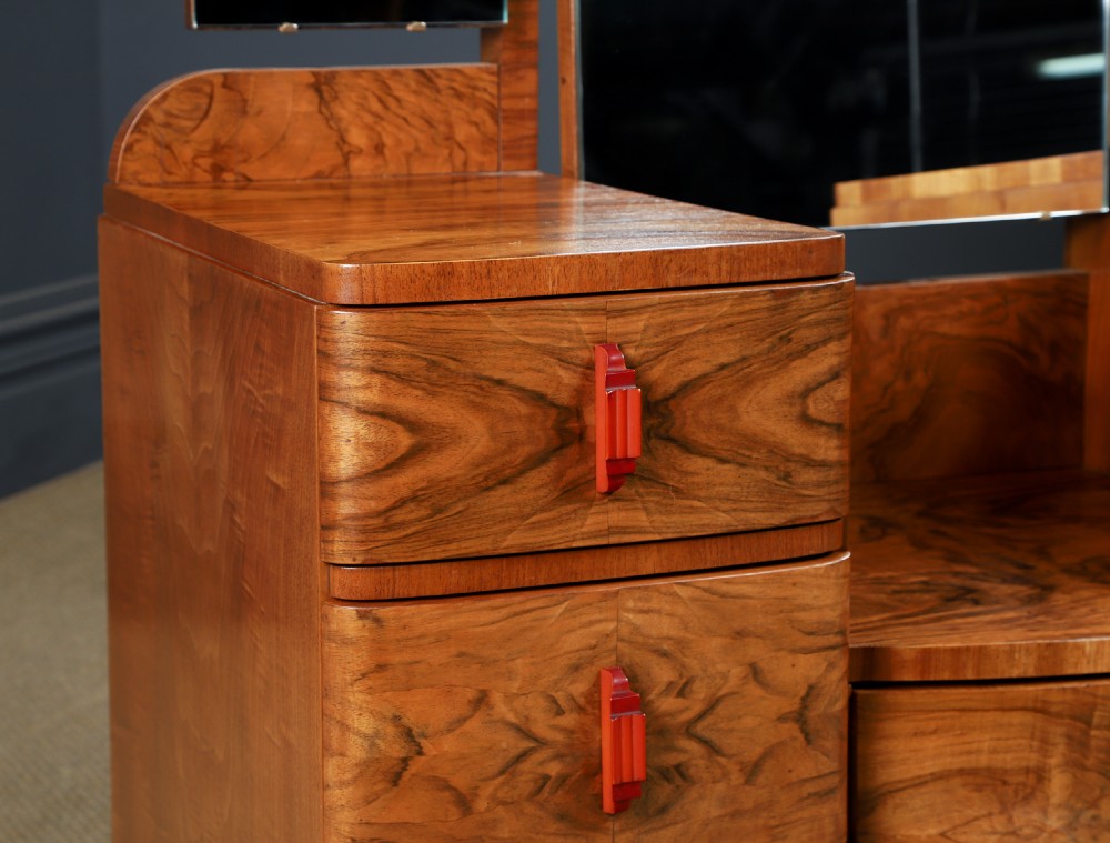 An Art Deco figured walnut dressing table featuring twin pedestal drawers, a central curved drawer, red handles, and a three-panel upright mirror. View IV