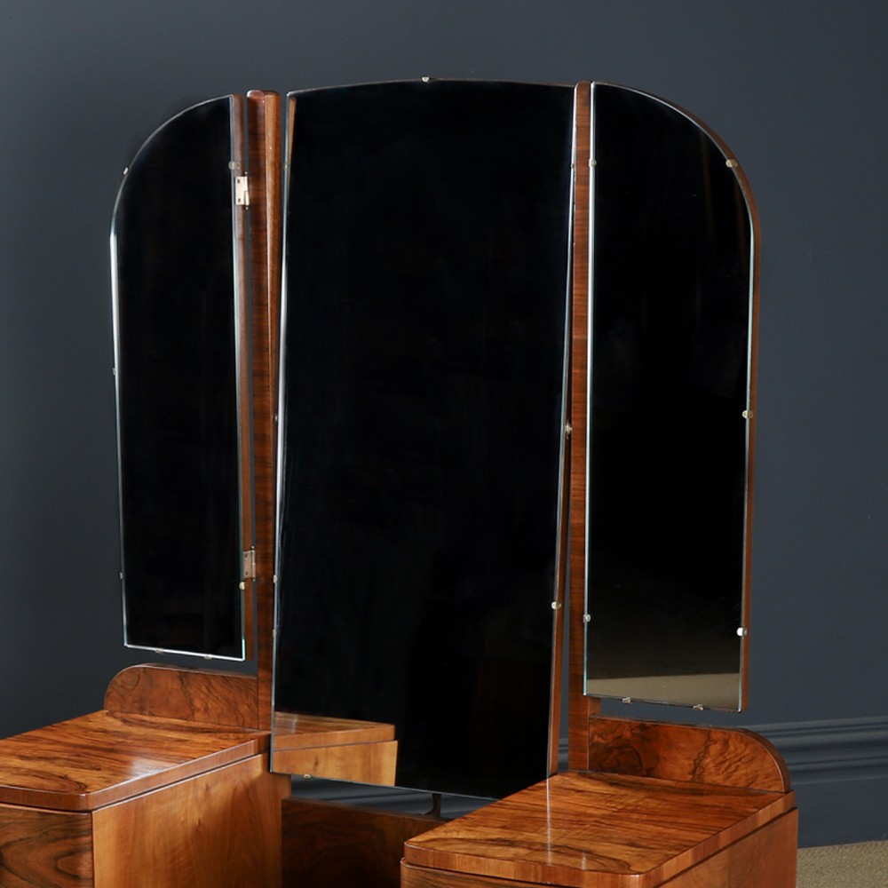 An Art Deco figured walnut dressing table featuring twin pedestal drawers, a central curved drawer, red handles, and a three-panel upright mirror. View IX