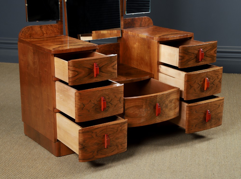An Art Deco figured walnut dressing table featuring twin pedestal drawers, a central curved drawer, red handles, and a three-panel upright mirror. View XII