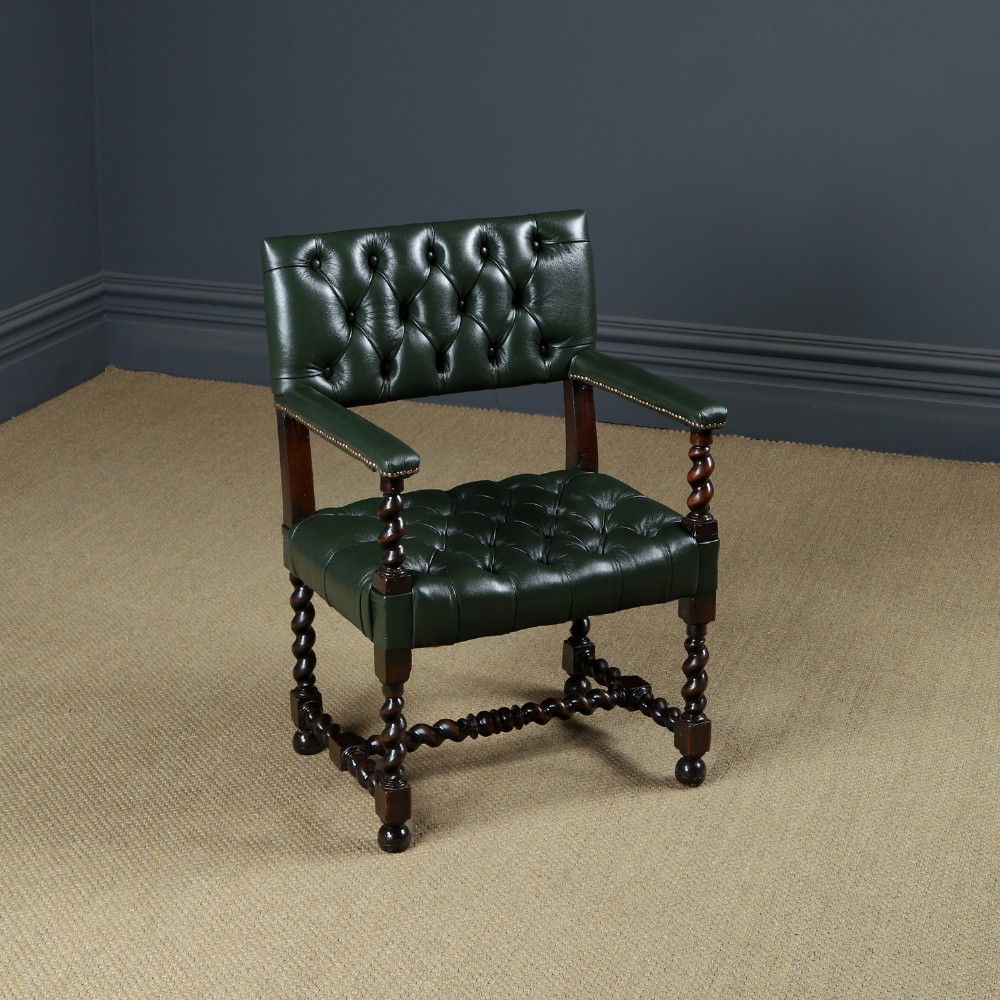 An antique 17th-century style dark oak armchair featuring deep-buttoned green leather upholstery, brass stud trim, and barley-twist turned legs and stretchers.