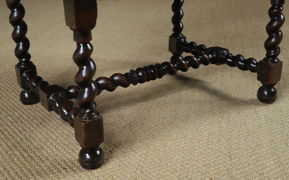 An antique 17th-century style dark oak armchair featuring deep-buttoned green leather upholstery, brass stud trim, and barley-twist turned legs and stretchers. View IV
