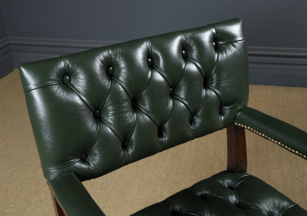An antique 17th-century style dark oak armchair featuring deep-buttoned green leather upholstery, brass stud trim, and barley-twist turned legs and stretchers. View VI