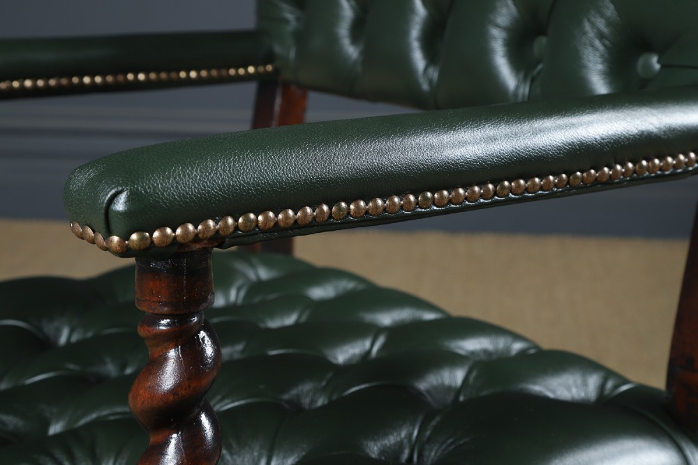 An antique 17th-century style dark oak armchair featuring deep-buttoned green leather upholstery, brass stud trim, and barley-twist turned legs and stretchers. View VII