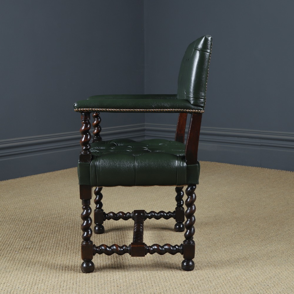 An antique 17th-century style dark oak armchair featuring deep-buttoned green leather upholstery, brass stud trim, and barley-twist turned legs and stretchers. View XI