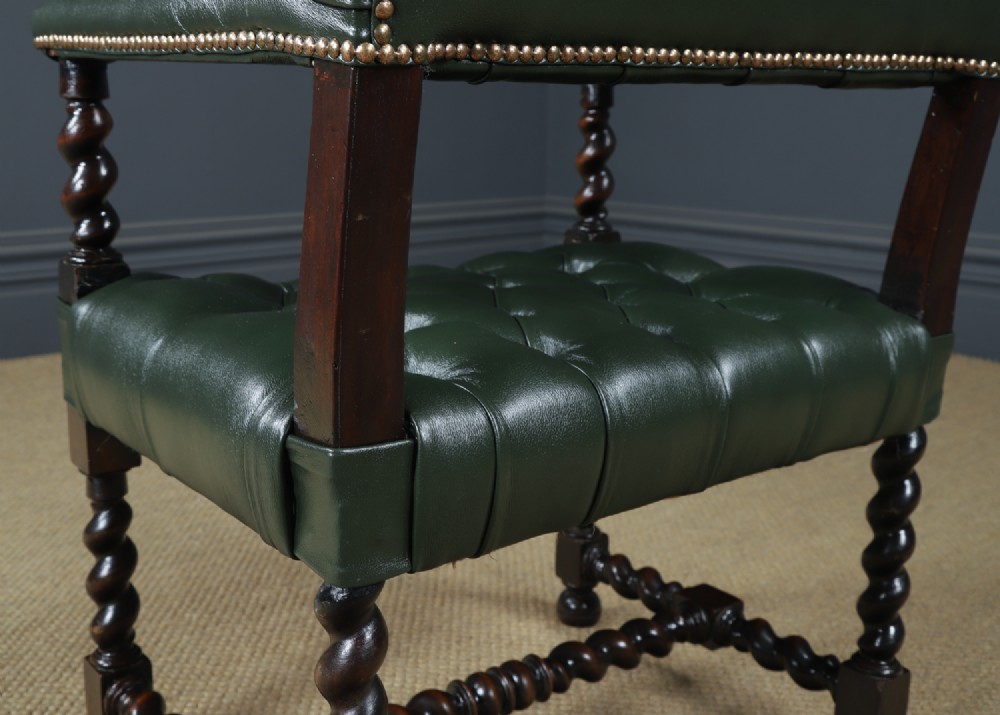 An antique 17th-century style dark oak armchair featuring deep-buttoned green leather upholstery, brass stud trim, and barley-twist turned legs and stretchers. View XIV