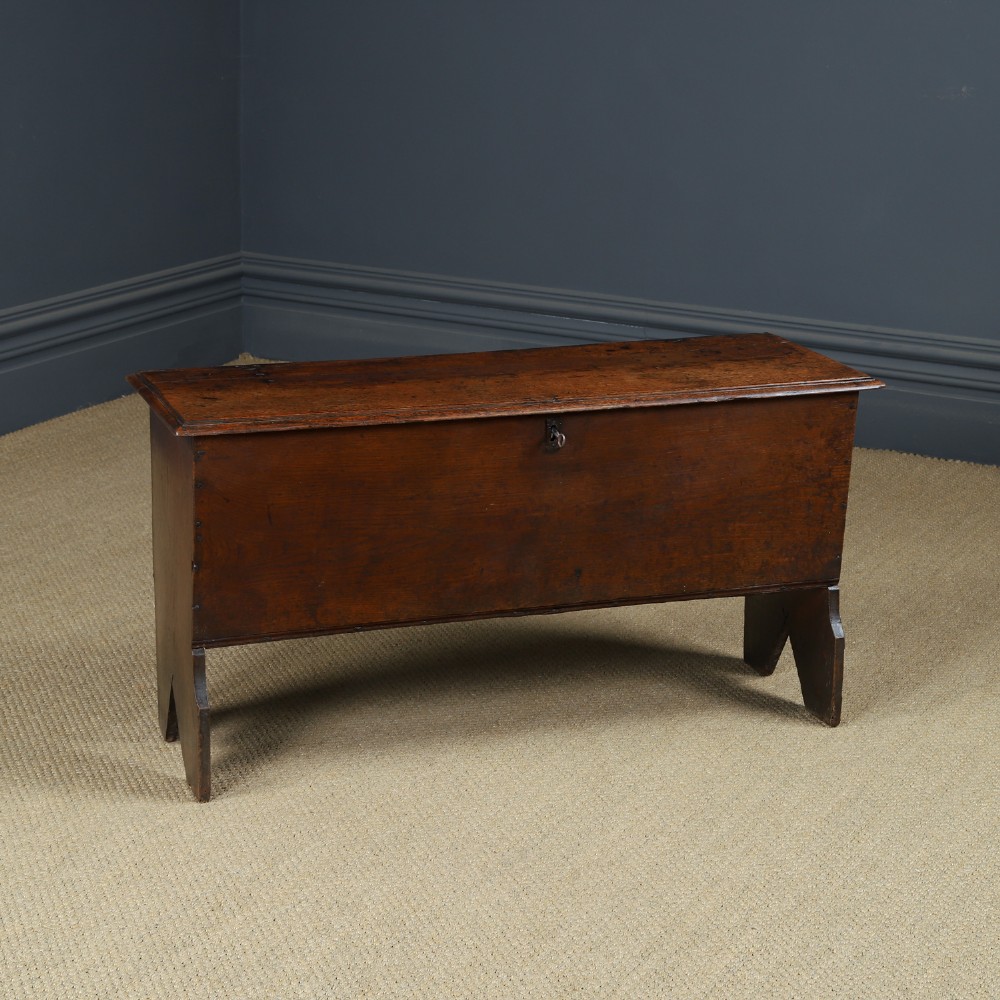 A rectangular dark brown oak six-plank coffer featuring V-cut side legs and iron keyhole escutcheon detail.