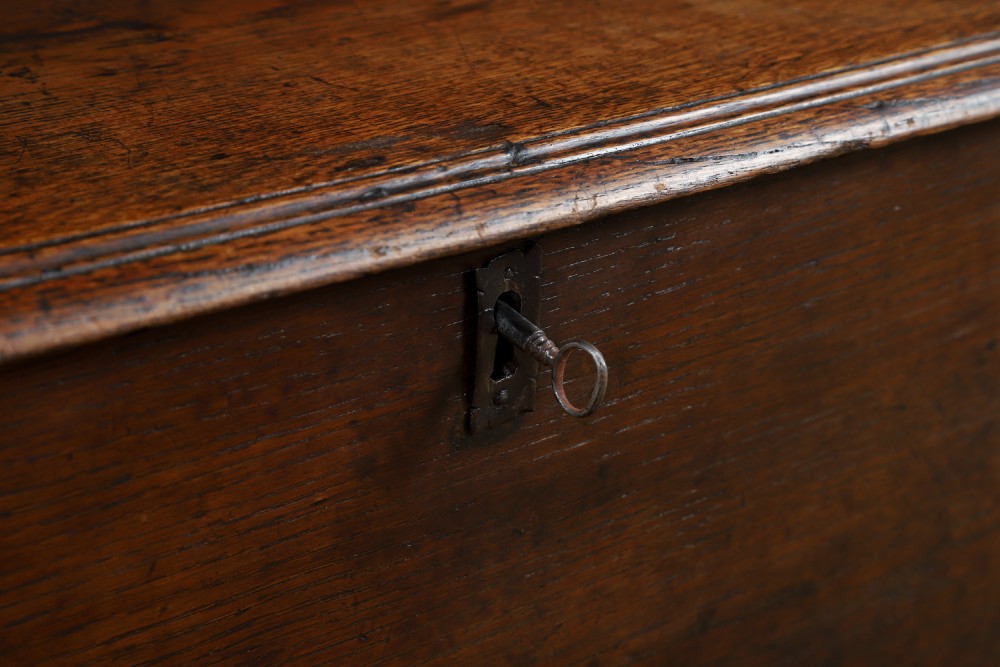 A rectangular dark brown oak six-plank coffer featuring V-cut side legs and iron keyhole escutcheon detail. View III