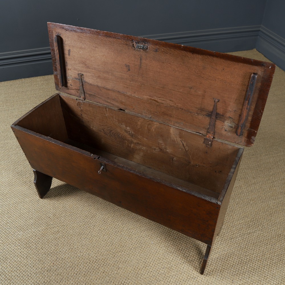 A rectangular dark brown oak six-plank coffer featuring V-cut side legs and iron keyhole escutcheon detail. View V