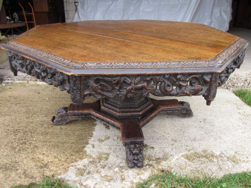 Superb 19th Century Carved Oak Octagonal Tilt Top Centre Dining Table with Carved Edge and Fret Carved Mythical Creature Frieze with Drop Finials, Carved Studded Tapering Column, Carved Quadruple Base Set on Castors